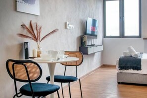 A modern room with a dining table, chairs, a TV, and a bed. - Riveria City near KL Sentral with Sky Infinity Pool by COBNB (Kuala Lumpur)