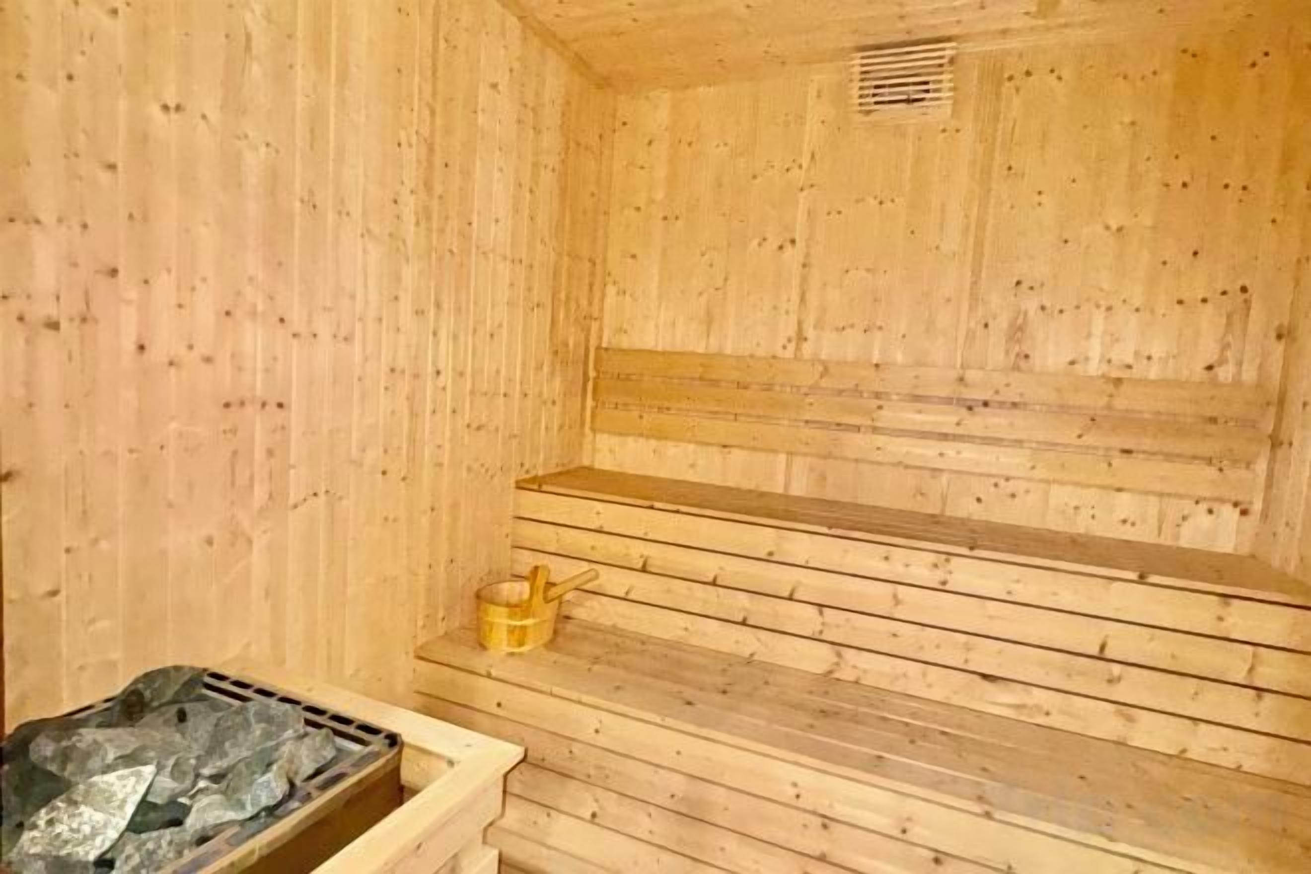 Uma sauna de madeira com bancos e um banco de madeira com um recipiente.