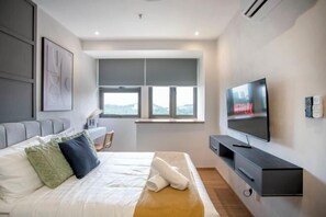 A modern hotel room with a bed, a TV, a window, and a desk. - Riveria City near KL Sentral with Sky Infinity Pool by COBNB (Kuala Lumpur)