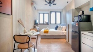 A compact hotel room with a bed, a small kitchenette, a dining area with a table and chairs, and a ceiling fan. - Riveria City near KL Sentral with Sky Infinity Pool by COBNB (Kuala Lumpur)