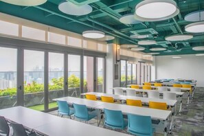 A conference room with tables and chairs, large windows, and a view of the city. - Riveria City near KL Sentral with Sky Infinity Pool by COBNB (Kuala Lumpur)