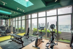 A gym with various exercise equipment, large windows, and a view of the city. - Riveria City near KL Sentral with Sky Infinity Pool by COBNB (Kuala Lumpur)