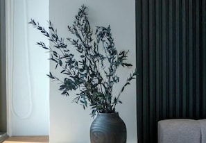 Ein Zimmer mit einem großen Fenster, einem dunklen Vorhang und einem grauen Sofa.