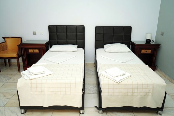Two single beds with black headboards, white linens, and a checkered bedspread. There are wooden nightstands with lamps and a wicker chair. - HOTEL BLISS (Bucharest)