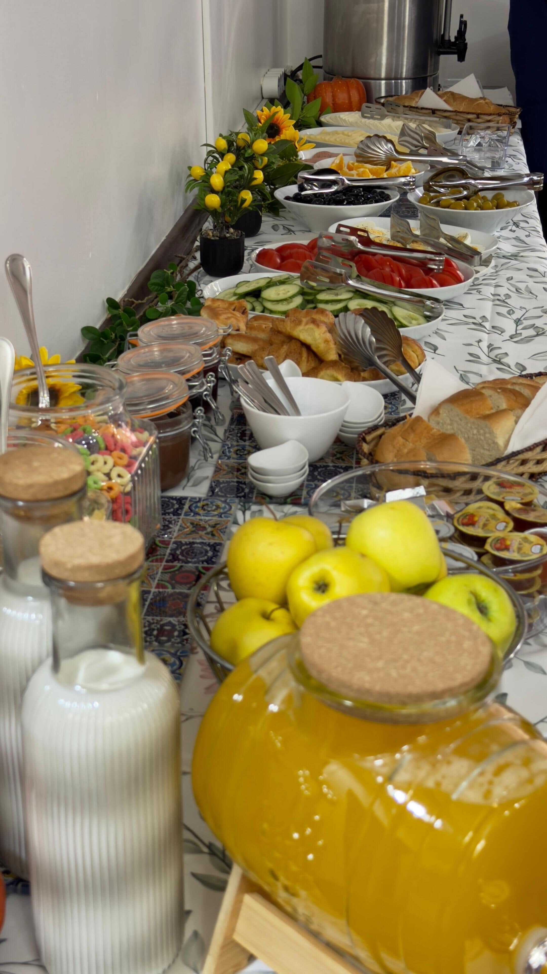 A buffet table with various food items, including fruits, vegetables, and bread.