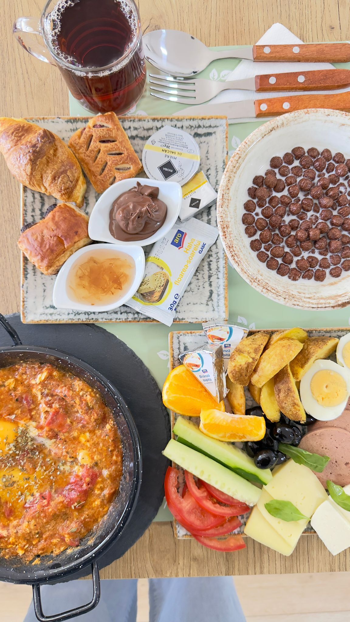 A table with a variety of foods including pastries, a dish with eggs, cheese, and vegetables, and a pot of stew.