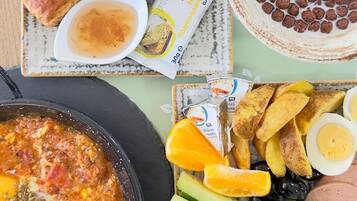 Una mesa con diversos alimentos, entre ellos pasteles, un plato de huevos, queso y verduras, y una olla de guiso.