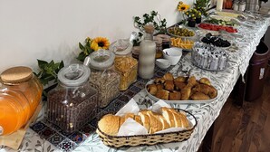 A buffet table with various food items, including fruits, vegetables, and pastries, set up in a room with framed botanical prints on the wall.