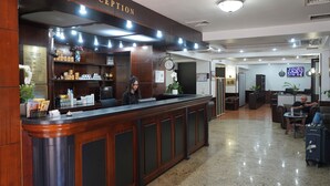 A reception area with a wooden reception desk, a clock, and a seating area with a TV.