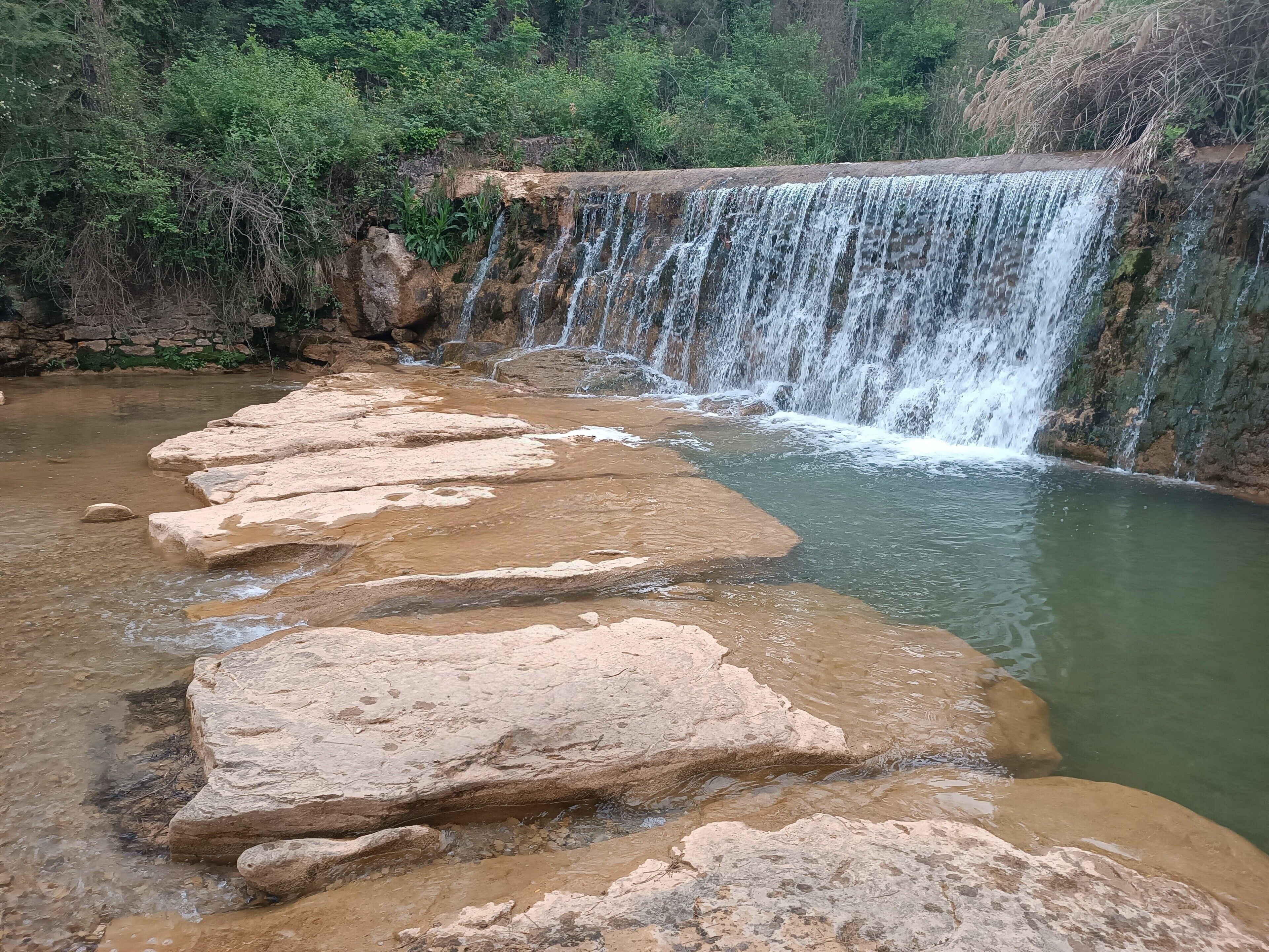 A natural waterfall with a series of large rocks in the foreground.