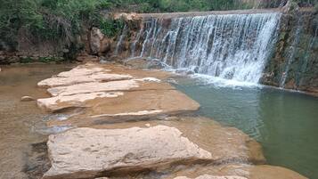 A natural waterfall with a series of large rocks in the foreground.