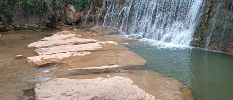 A natural waterfall with a series of large rocks in the foreground.