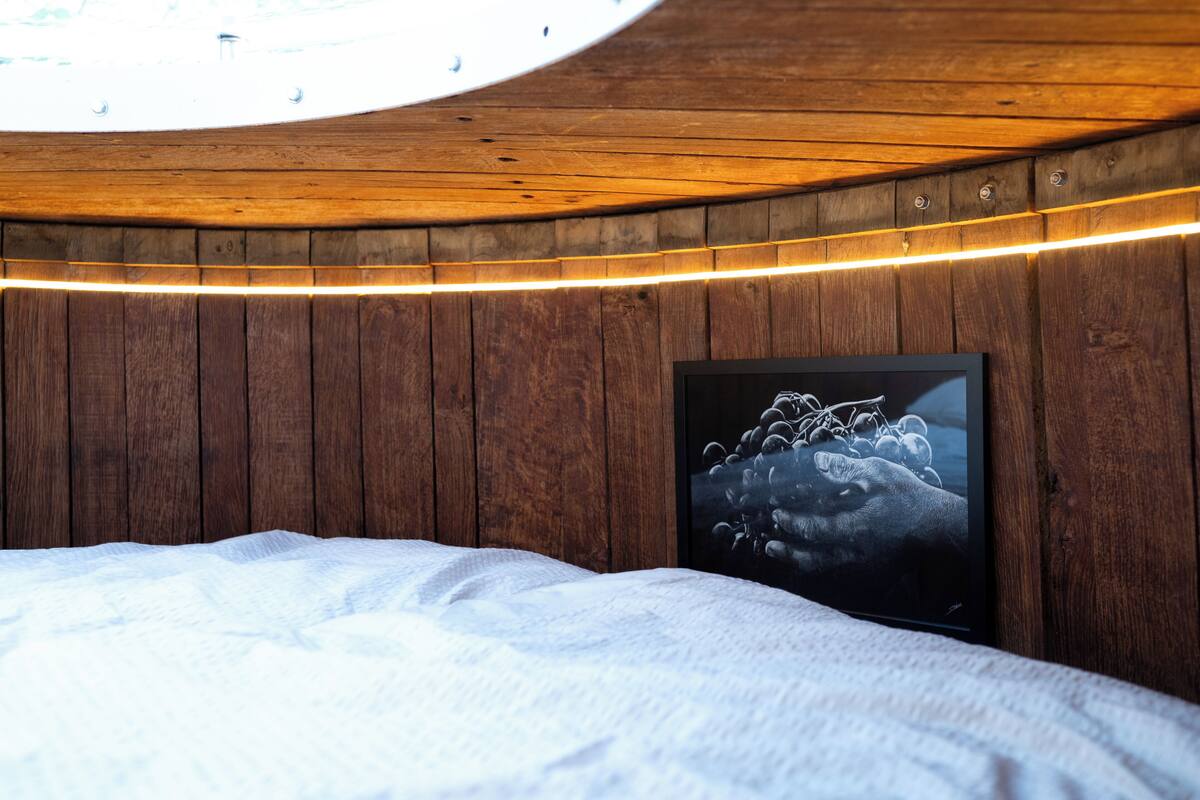 Ein Zimmer mit Holzwänden, einem Bett mit weißer Bettwäsche und einem gerahmten Bild an der Wand.