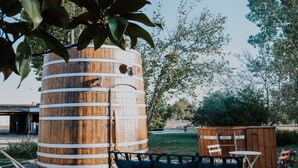 A rustic outdoor seating area with a wooden barrel, a metal bench, and a small table. - Le Nid du Coucou (Cocumont)