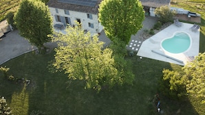 An aerial view of a house with a swimming pool, solar panels, and a well-maintained lawn. - Le Nid du Coucou (Cocumont)