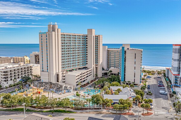 A hotel with multiple buildings, a swimming pool, and a view of the ocean.