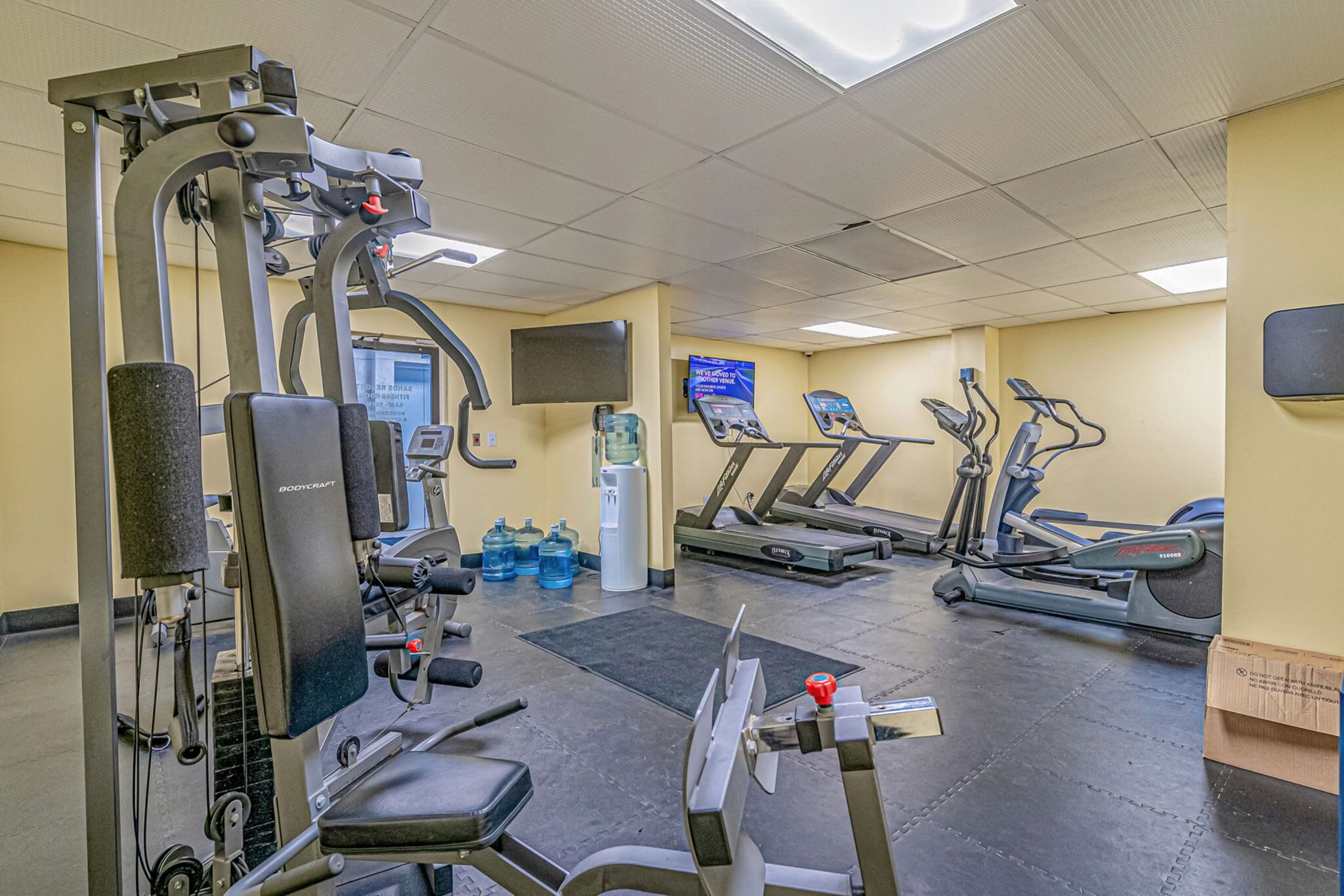 A gym with cardio machines, weight machines, and a water dispenser.