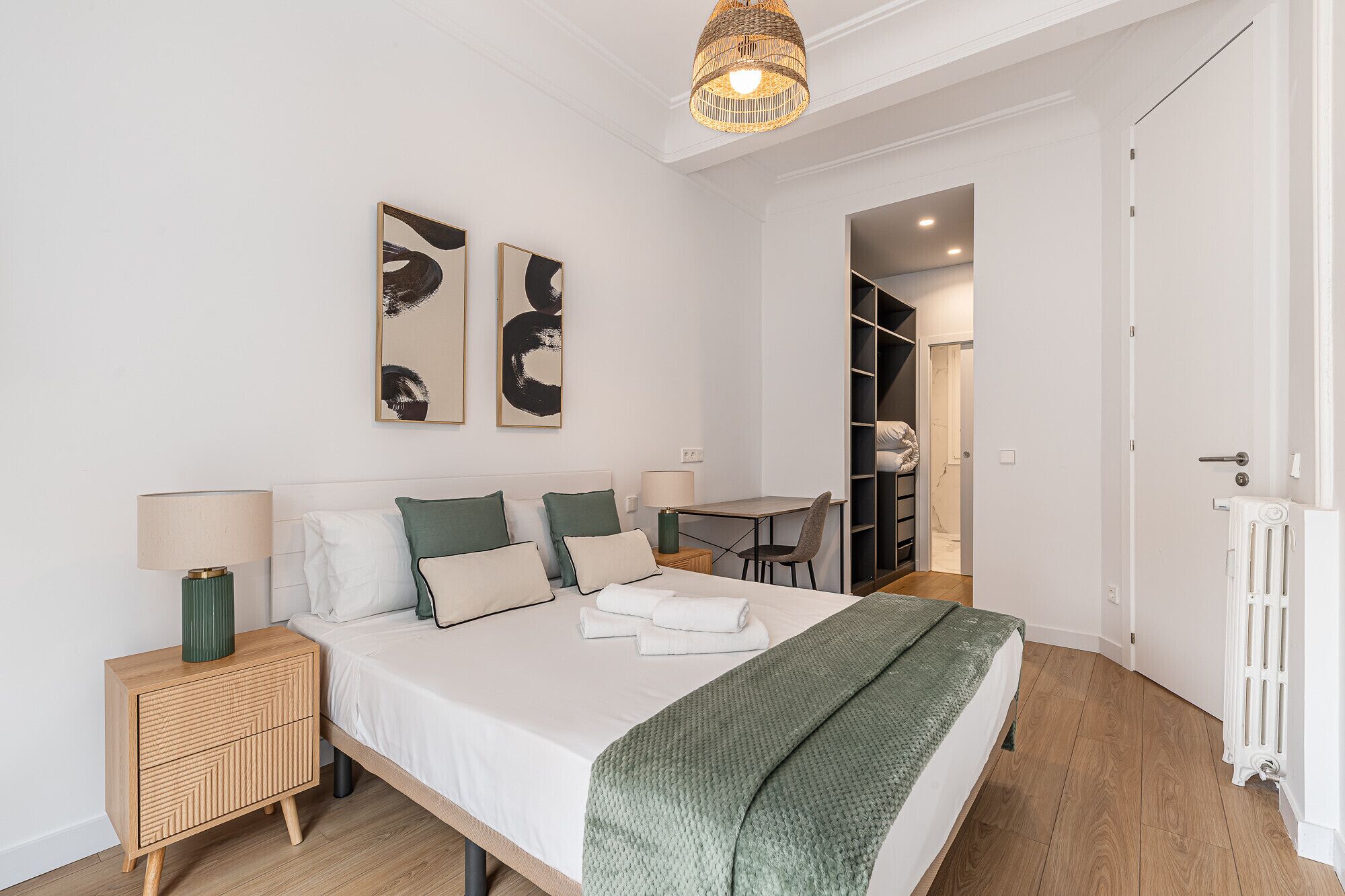 Un dormitorio moderno con cama, mesitas de noche, escritorio y armario.