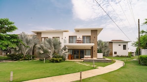 A modern two-story house with a well-maintained lawn, a patio with outdoor furniture, and a clear sky.