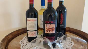 Three wine bottles and two wine glasses on a wooden tray with a lace doily.