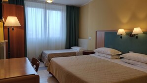 A hotel room with two single beds, a wooden desk, a chair, and a table. - Albergo Conte Max (Capracotta)