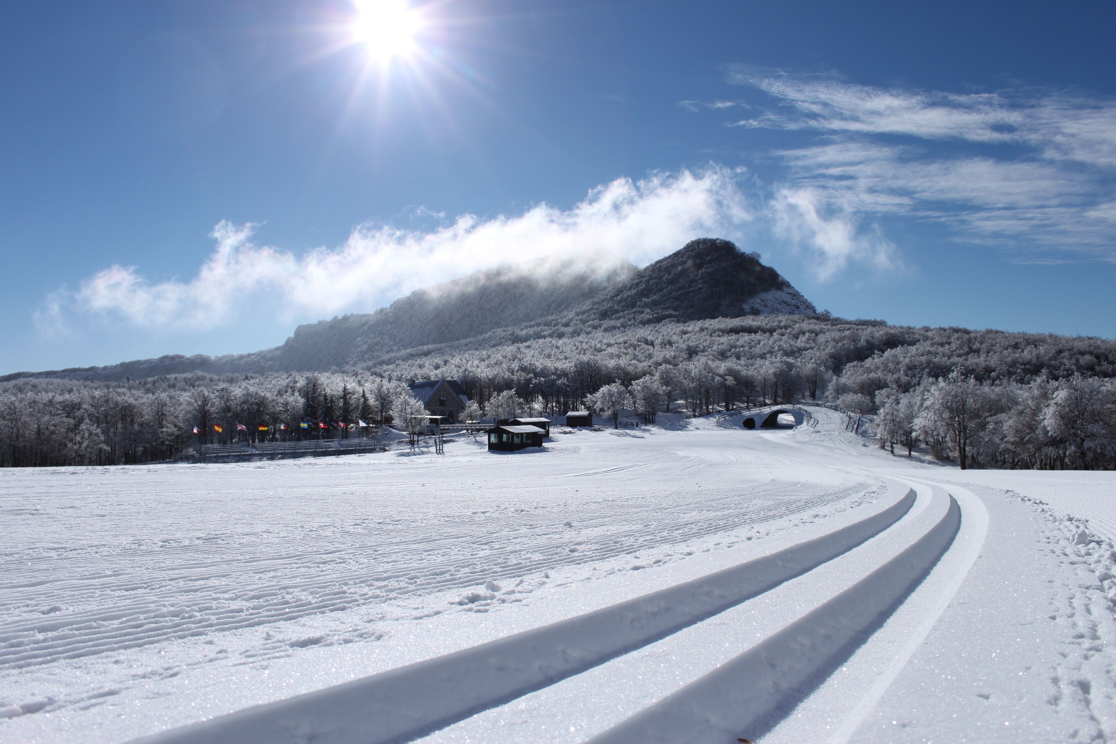 Schneebedeckte Landschaft mit Berg, Straße und einem kleinen Gebäude.