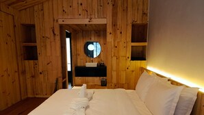 A wooden room with a bed, a round mirror, and a sink. - The Himalayan Phakding (Phakding)