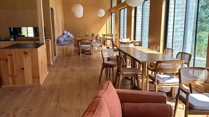 A spacious wooden interior with a dining area, large windows, and a sofa. - The Himalayan Phakding (Phakding)