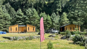 A wooden cabin with a stone wall and a flag in front. - The Himalayan Phakding (Phakding)