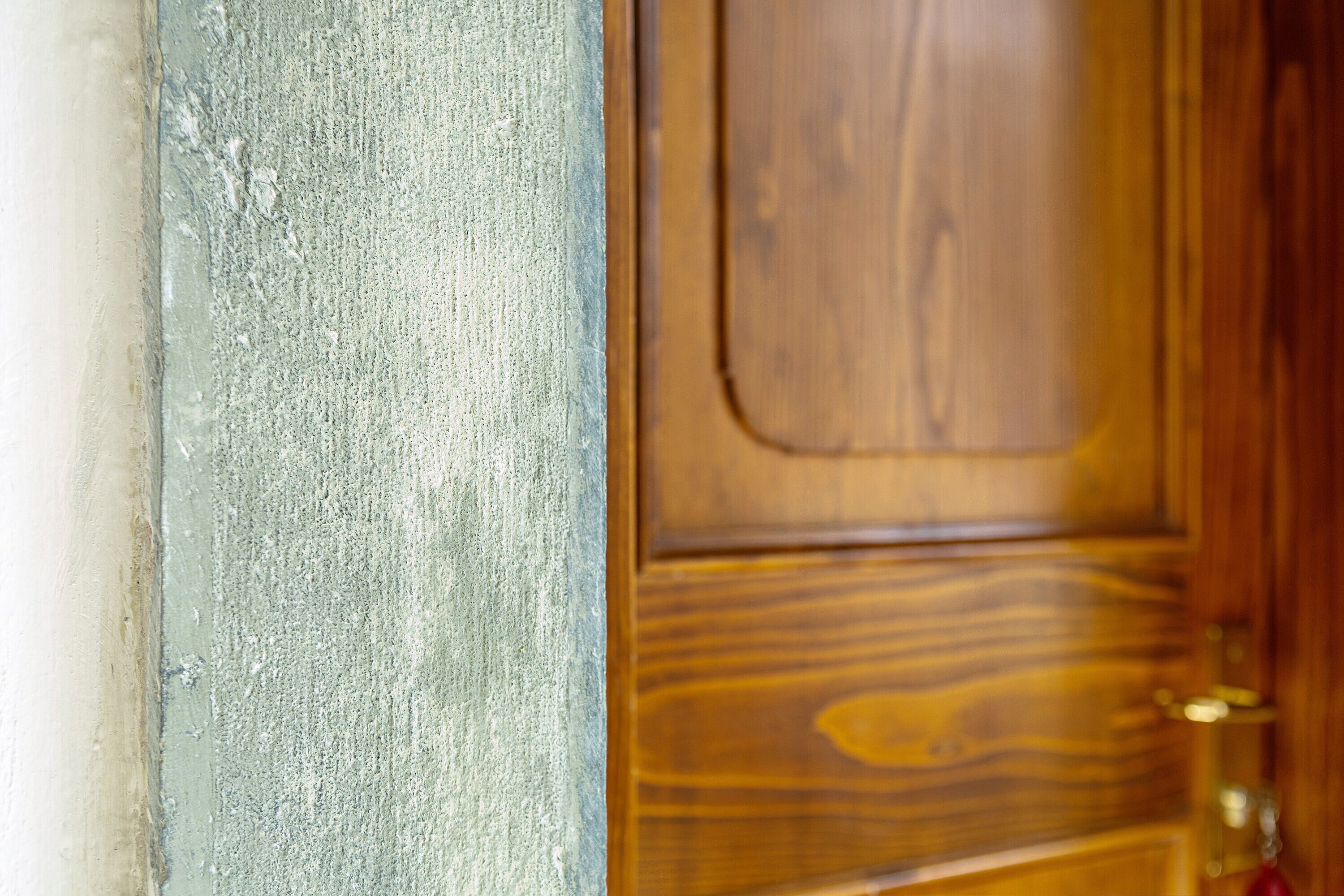 A wooden door with a brass handle and a textured wall.
