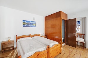 Un dormitorio con una cama de madera, una mesita de noche, un armario de madera y un cuadro en la pared.