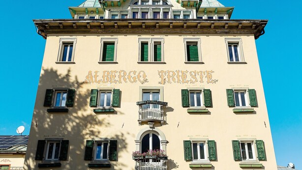 Un edificio con la inscripción 'ALBERGO PRISTI' y un balcón lleno de flores.