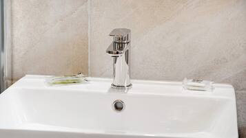 Un lavandino bianco con rubinetto cromato e dispenser per sapone.