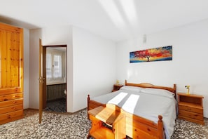 Ein Schlafzimmer mit einem hölzernen Bett, einem Nachttisch, einer Kommode und einem Bild an der Wand.