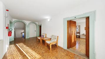 Un pasillo con piso estampado, sillas de madera y una puerta que da a otra habitación.