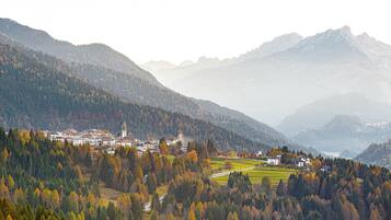 A mountainous landscape with a village, buildings, and autumn foliage.