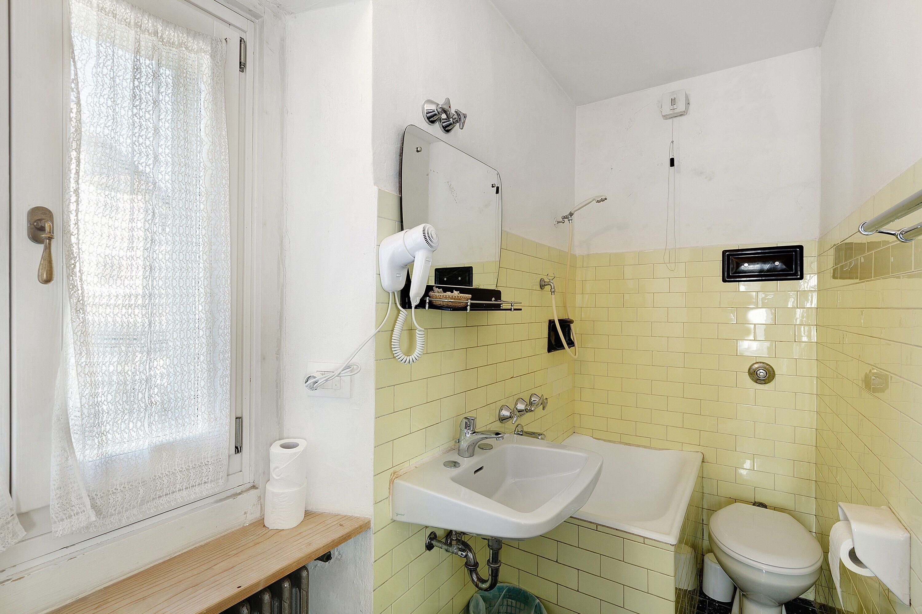 A bathroom with a sink, toilet, and a mirror.