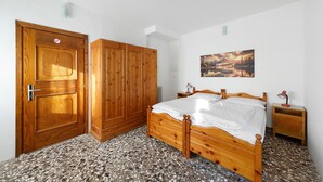 A bedroom with a wooden bed, wardrobe, and a painting on the wall.