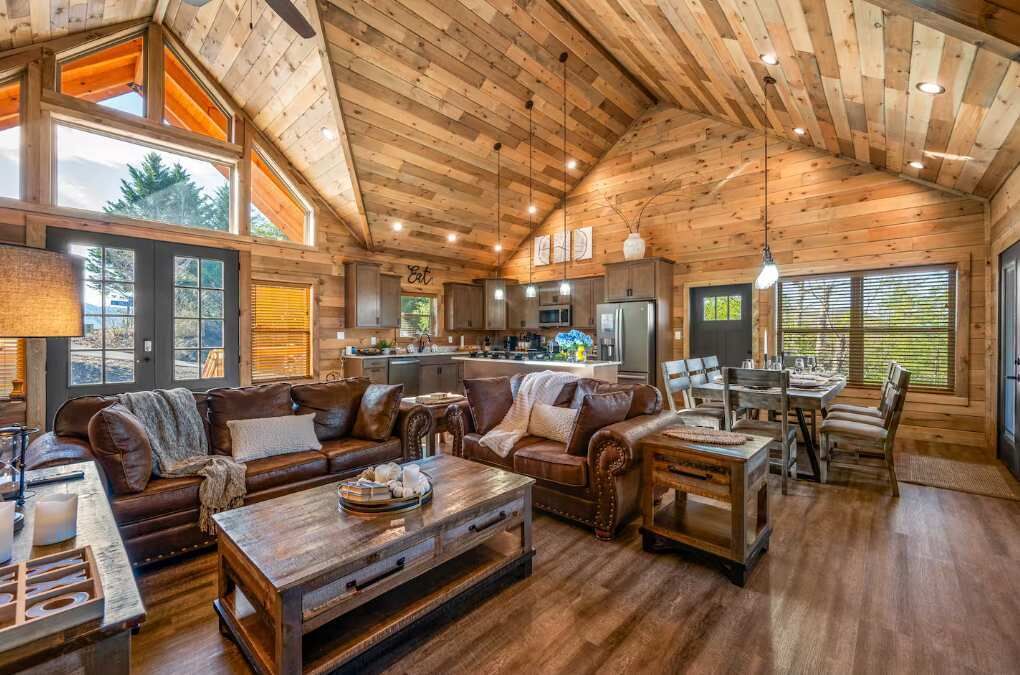 A spacious living area with a large wooden ceiling, a cozy fireplace, and a dining area with a wooden table and chairs.