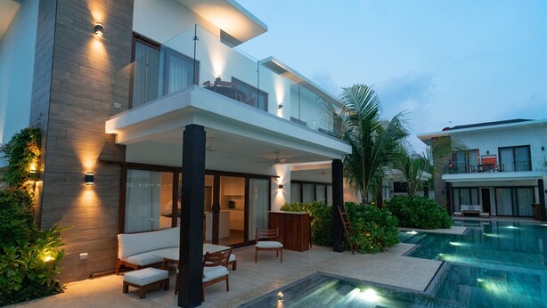 A modern two-story house with a swimming pool, outdoor seating, and a well-lit balcony. - Luxury Villa w Direct Pool Entry Monterrico (Taxisco)