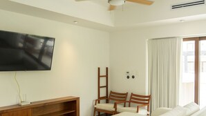 A modern living room with a flat-screen TV, wooden furniture, and a ceiling fan. - Luxury Villa w Direct Pool Entry Monterrico (Taxisco)