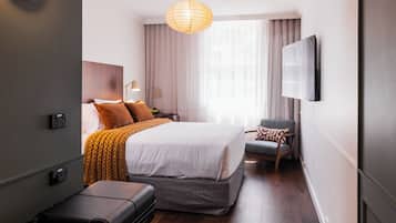A hotel room with a bed, a chair, a TV, and a suitcase.