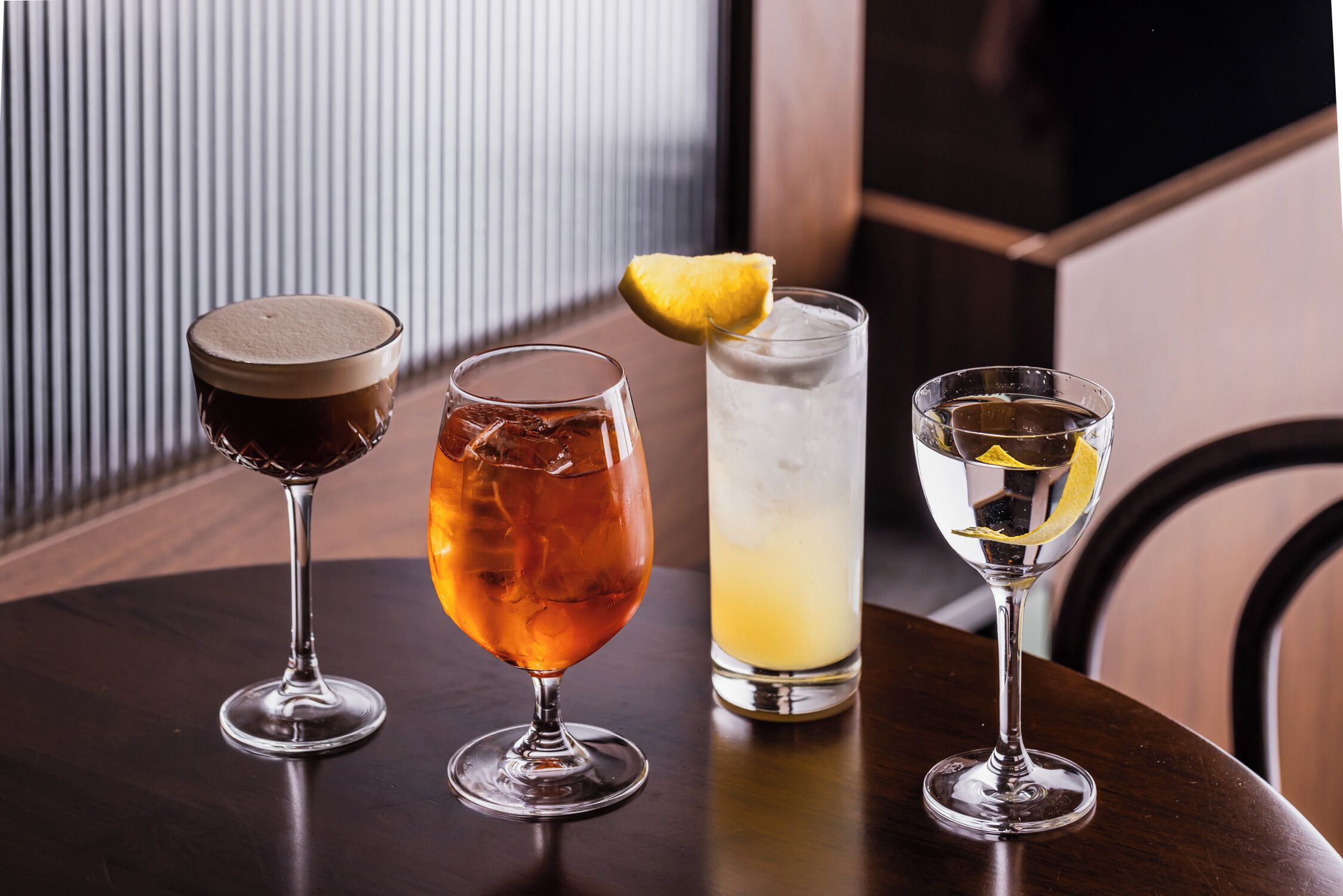 Tres vasos de bebidas sobre una mesa de madera con un fondo a rayas.