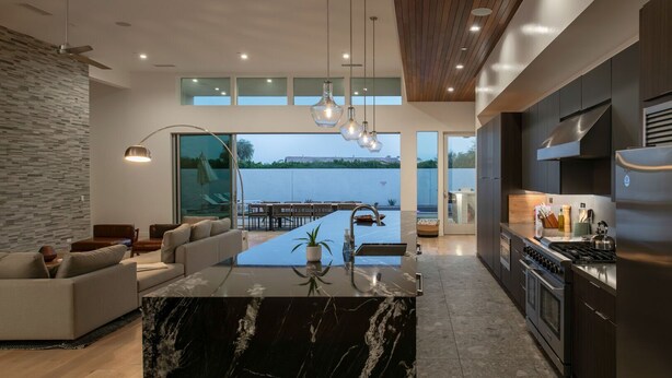 A modern kitchen with a marble island, built-in appliances, and a view of a lake. - Carbon @ Elemento49 - Pool & Spa - Sleeps 16 (Indio)