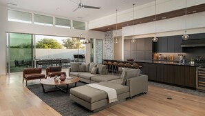 A modern living room with a sectional sofa, a coffee table, and a dining area with chairs. - Carbon @ Elemento49 - Pool & Spa - Sleeps 16 (Indio)