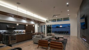 A modern kitchen with a central island, a dining area with a wooden table, and a living room with a sofa and coffee table. - Neon @ Elemento49 - Pool & Spa - Sleeps 16 (Indio)