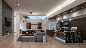 A modern kitchen with a large island, dark cabinetry, and pendant lighting. - Neon @ Elemento49 - Pool & Spa - Sleeps 16 (Indio)