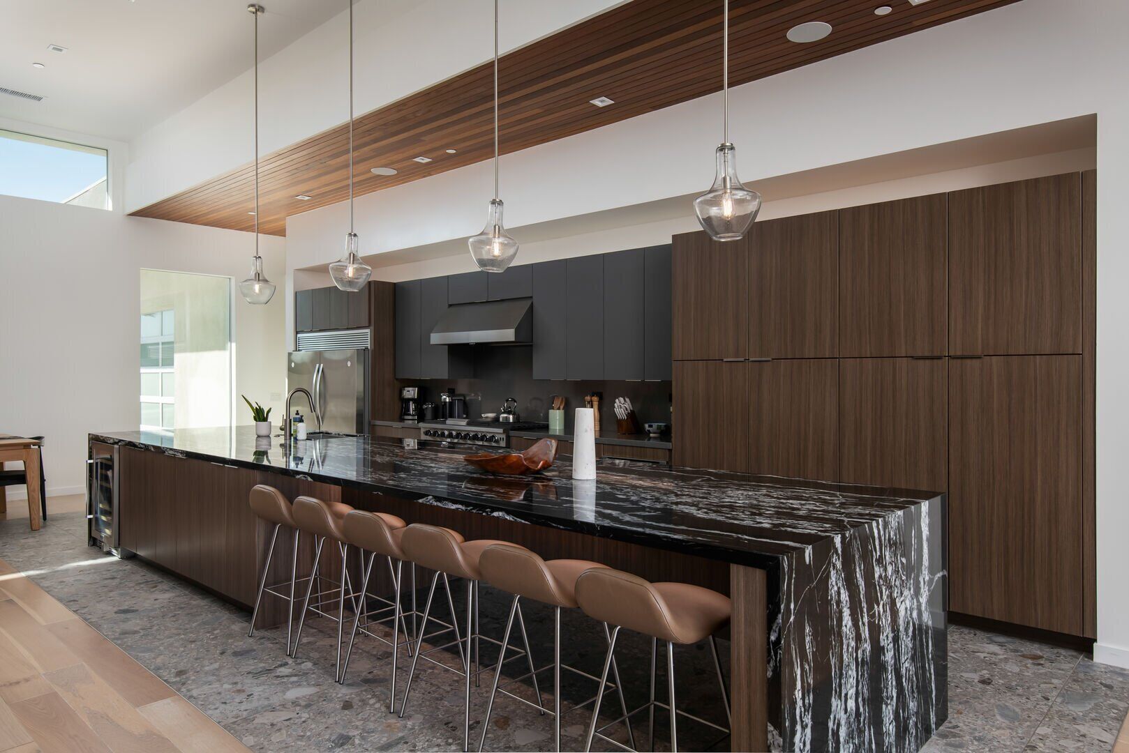Una cocina moderna con una isla grande, taburetes de bar e iluminación colgante.
