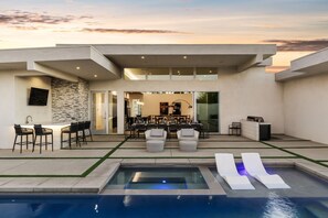 Ein moderner Außenbereich mit Pool, Sitzgelegenheiten und Essbereich.