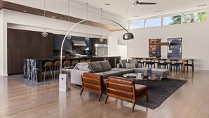 A modern open-plan living area with a kitchen, dining space, and seating arrangement. - Oxygen @ Elemento49 - Pool & Spa - Sleeps 16 (Indio)